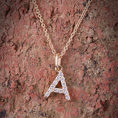 letter gold necklace on stone